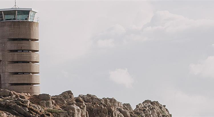 Photo of cliff headland with old german radio tower, sea in background with patchy sun and clouds